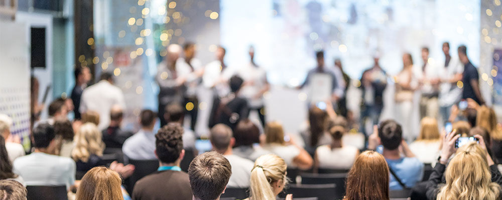 Large corporate event with award recipients being rewarded up on stage and fireworks going off behind them.